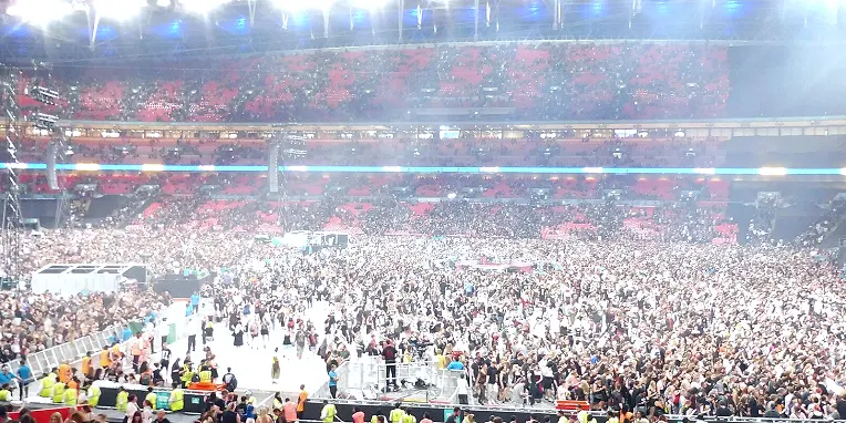 大型球场内夜色下人群与旗帜的画面(中场人数优势:德尚与吉瓦什的看管任务)